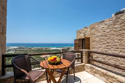 a table and chairs on a balcony with a bowl of fruit at The Stonemade Houses in Falasarna