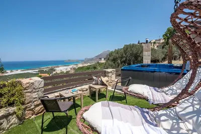 a patio with a hammock and a view of the ocean at The Stonemade Houses in Falasarna