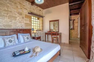 a bedroom with a bed and a table in a room at The Stonemade Houses in Falasarna