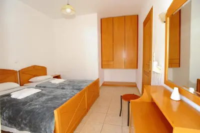 a bedroom with two beds and a sink and a mirror at Evilion hotel in Stalos