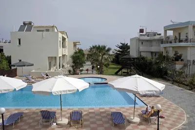 a swimming pool with chairs and umbrellas at Evilion hotel in Stalos