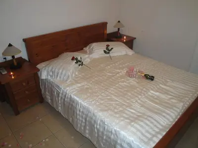a bed with two roses on it with two night stands at Kandania Apartments in Kántanos