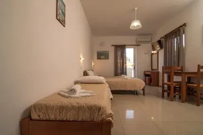 a hotel room with two beds and a dining room at Sifis Studios in Palaiochóra