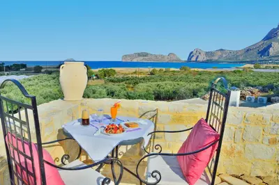 a table and chairs on a patio with a view of the ocean at Koukis House With Sea View in Falasarna