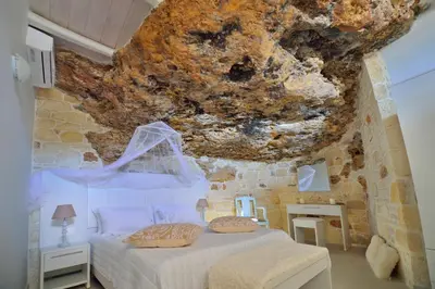 a bedroom with a bed and a stone wall at Koukis House With Sea View in Falasarna