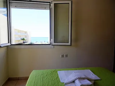 a bedroom with a bed and a window with a view at Platanias House on the Beach in Plataniás