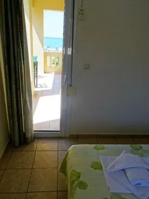 a room with a bed and a door to a balcony at Platanias House on the Beach in Plataniás