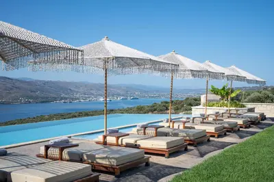 a row of lounge chairs and umbrellas next to a pool at Elements Villa in Galangádhos