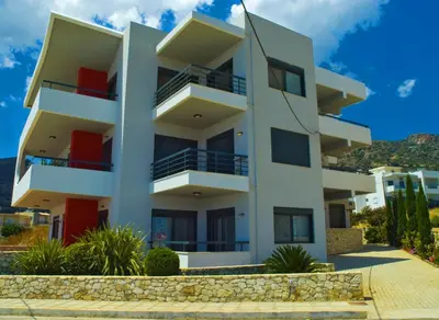 a white apartment building with red balconies at Caravella Luxury Apartments in Palaiochóra