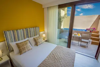 a bedroom with a white bed and a balcony at Aretousa Suites in Chania Town