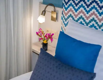a bed with a blue pillow and a vase with flowers at Aretousa Suites in Chania Town