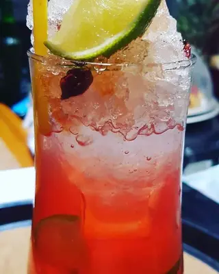 a drink with a slice of lime on a table at Haris Studios in Palaiochóra