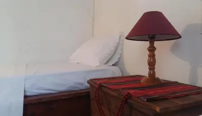 a lamp sitting on a table next to a bed at Bendeni Cottage in Megála Khoráfia