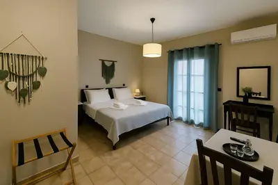 a bedroom with a white bed and a table and a window at Nicolas Beach in Palaiochóra