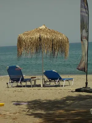 two chairs and an umbrella on the beach at Hippokratis Apartments in Gerani Chanion