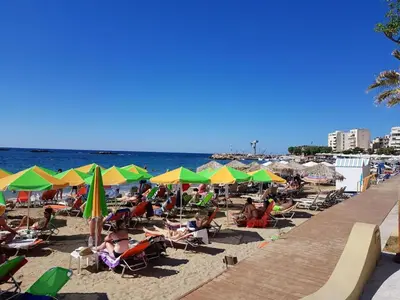 a beach with people sitting in chairs and umbrellas at Mirsini's Apartment in Chania center in Chania Town