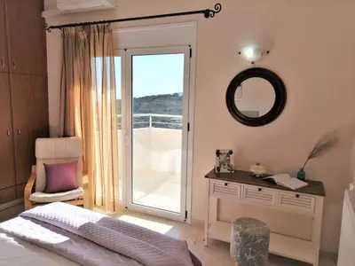 a bedroom with a bed and a mirror and a balcony at Villa Aeolus with private overflow, endless, heated pool in Prinés