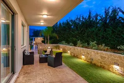 an outdoor patio with chairs and a stone wall at Kagiemar Luxury House in Perivólia