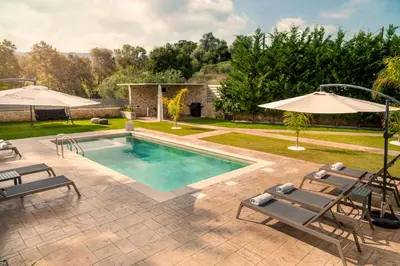 a swimming pool with chairs and an umbrella at Kagiemar Luxury House in Perivólia