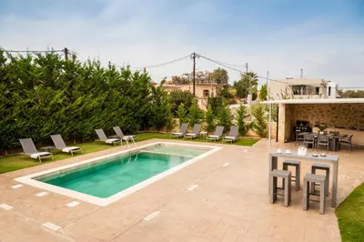 a swimming pool in a yard with chairs and a table at Amaen Luxury House in Perivólia