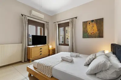 a bedroom with a white bed and a television at Casa Veranda - 3 Bedroom House with BBQ & Backyard in Chania Town