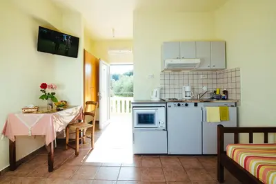 a kitchen with a table and a white refrigerator at Kalithea Apartments - Heated Pool in Kalyves