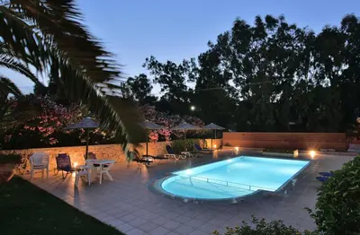 a swimming pool in a backyard at night at Flisvos Rooms in Palaiochóra