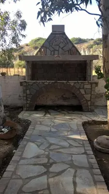an outdoor brick oven with a stone patio at Flisvos Rooms in Palaiochóra
