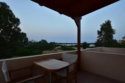 a table and chairs on a balcony with a bath tub at Flisvos Rooms in Palaiochóra