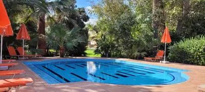a swimming pool with chairs and umbrellas at Marita's Apartments in Agia Marina Nea Kydonias