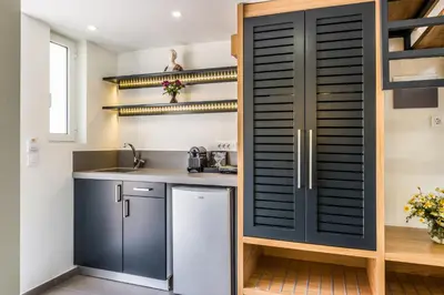 a kitchen with blue cabinets and a refrigerator and shelves at Forum Suites in Kato Daratso