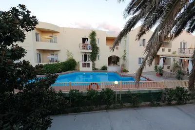 an apartment building with a swimming pool in front of it at Lambrinos Suites in Plataniás