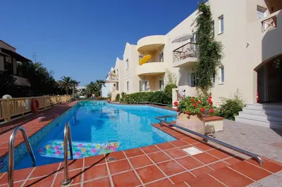 a swimming pool in front of a building at Lambrinos Suites in Plataniás