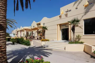 a building with palm trees in front of it at Lambrinos Suites in Plataniás