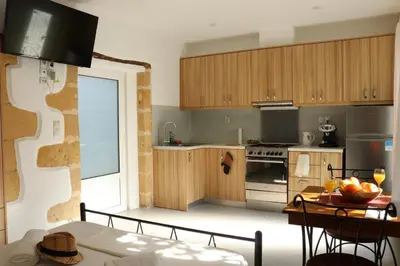 a kitchen with wooden cabinets and a table with a bowl of fruit at Grandma's Nest in Kissamos