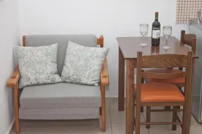 a dining room table with a couch and a table with wine glasses at Vaso Apartments in Plataniás