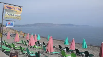 a group of chairs and umbrellas on a beach at Vaso Apartments in Plataniás