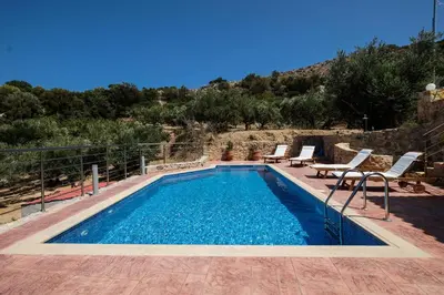 a swimming pool with two chairs and a table at Chania Village - Charoupia & Daphne Villas Private Pool - BBQ - Afrata in Afráta