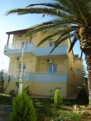 a yellow house with a palm tree in front of it at Despina Studios in Agia Marina Nea Kydonias