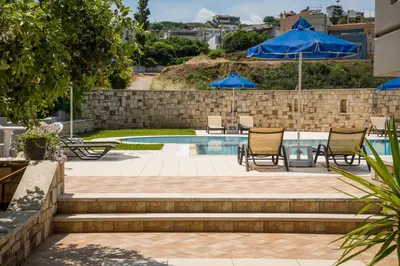 a patio with chairs and umbrellas next to a pool at IRINI STALOS Apartments in Stalos
