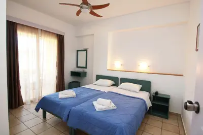a bedroom with a blue bed with two towels on it at Evropi Hotel in Plataniás