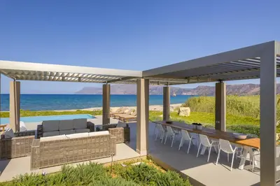an outdoor patio with a pergola and the ocean at Youphoria Beach Front Villas in Korfalónas