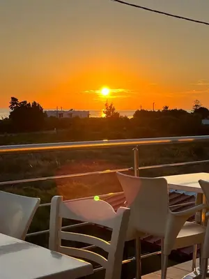 a sunset on a balcony with a table and chairs at Blue Sky in Frangokastello