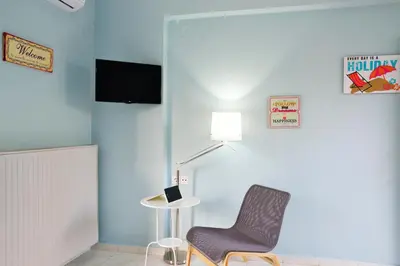 a blue room with a chair and a lamp at Katerina Apartments in Kato Daratso