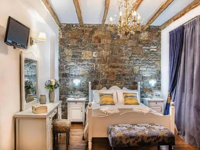 a bedroom with a bed and a stone wall at Private Pool & Garden Villa for 6 in Pemónia