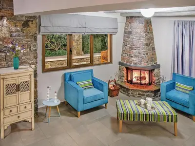 a living room with two blue chairs and a fireplace at Private Pool & Garden Villa for 6 in Pemónia
