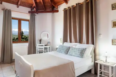 a bedroom with a white bed and a window at Andromia Studios & Apartments in Agia Marina Nea Kydonias