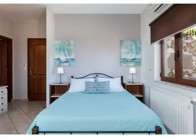 a bedroom with a bed with a blue bedspread at Andromia Studios & Apartments in Agia Marina Nea Kydonias