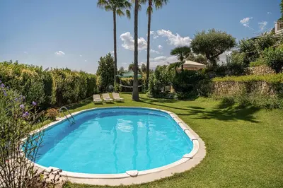 a swimming pool in a yard with two chairs at Andromia Studios & Apartments in Agia Marina Nea Kydonias
