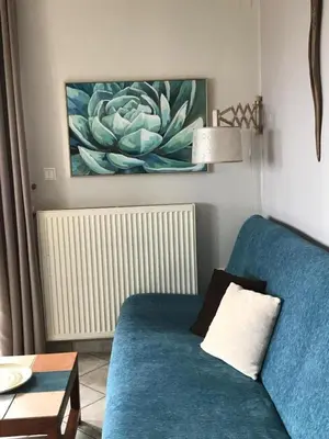 a blue couch in a living room with a painting at Andromia Studios & Apartments in Agia Marina Nea Kydonias